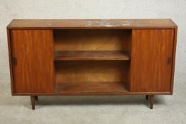 A circa 1960s teak sideboard, fitted with shelves and two sliding doors, on tapering cylindrical
