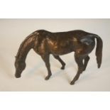 A bronze of a horse with head down, indistinctly signed to the underside. H.13 W.20 D.6 cm.