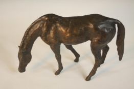A bronze of a horse with head down, indistinctly signed to the underside. H.13 W.20 D.6 cm.