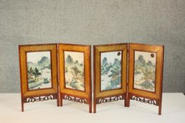 A pair of Chinese two fold table screens, each with central rectangular famille rose porcelain