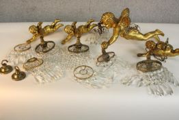 A set of four gilded flying cherub hanging lights, one larger than the other three, each holding a