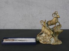 A brass figure group of two mountain ibex on a rocky outcrop along with a boxed silver handled