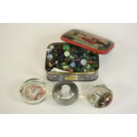 A tin of early 20th century and 19th century marbles along with three paperweights one with
