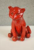 A large red glazed art pottery figure of a seated female lion, makers stamp to the base. H.29 W.29