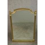 A Regency style gilt framed wall mirror, the shaped mirror plate flanked by reeded columns. H.86 W.