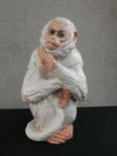 An Italian white glaze terracotta monkey holding its tail, stamped Made in Italy. H.40 W.22cm