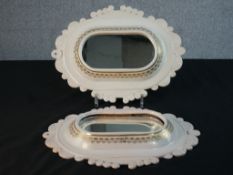 A pair of DRW white ceramic with gilded stencil design wall mirrors. Makers mark to the back. (One