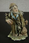 An Italian Capo di Monte barefoot tramp figure on a naturalistic base. H.27 W.15 D.14cm.