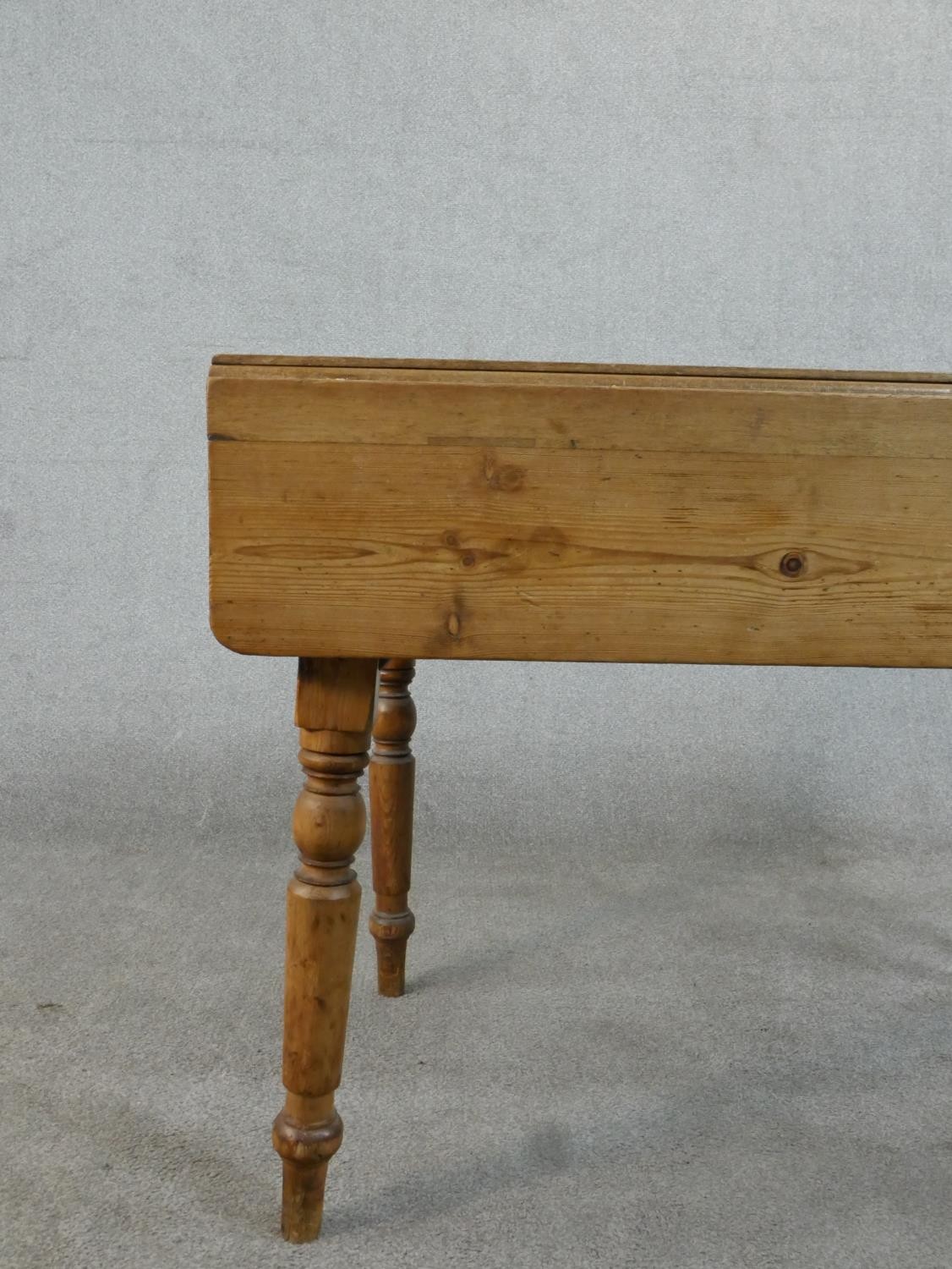A Victorian pine kitchen table, with one drop leaf over end drawers, on turned legs. H.71 W.109 - Image 2 of 7
