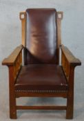 In the manner of Liberty & Co., an Arts and Crafts oak reclining armchair in leather studded