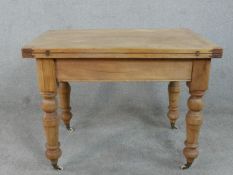 A Victorian pine kitchen table with hinged foldover top on turned baluster supports. H.72 W.132 D.