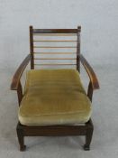 An early to mid 20th century fruitwood lounge chair, with open arms and a loose velour seat cushion,