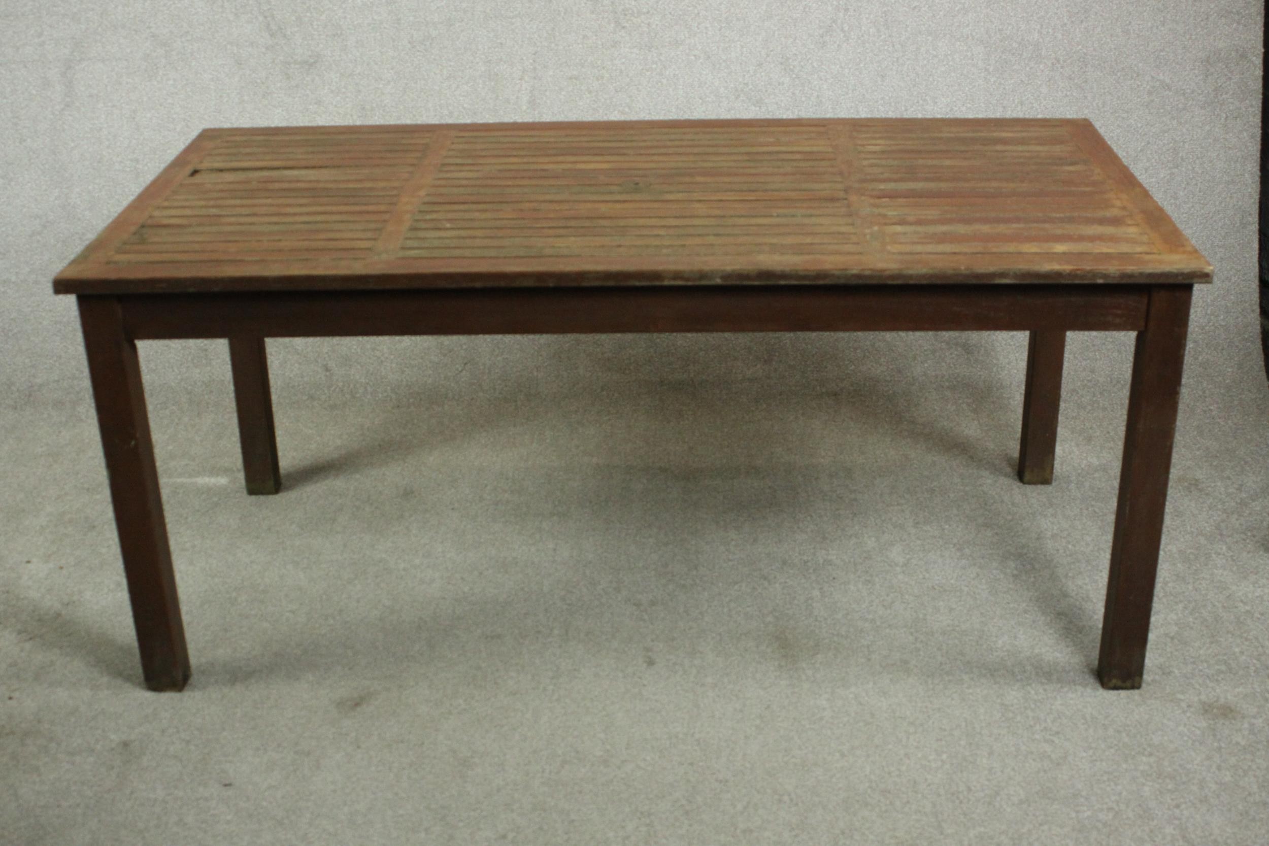A contemporary teak garden dining table, with a rectangular slatted top on square section legs. H.69
