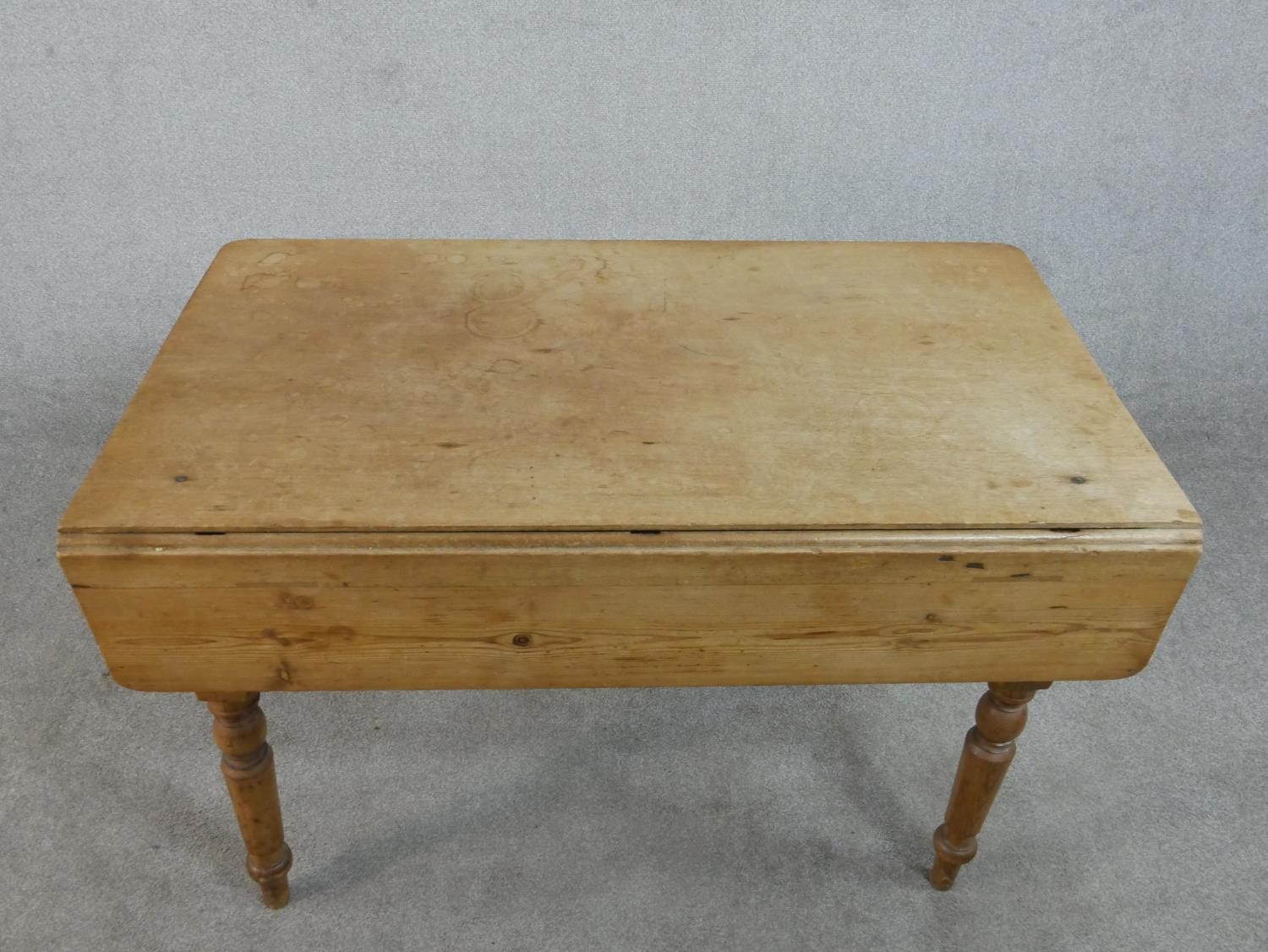 A Victorian pine kitchen table, with one drop leaf over end drawers, on turned legs. H.71 W.109 - Image 3 of 7