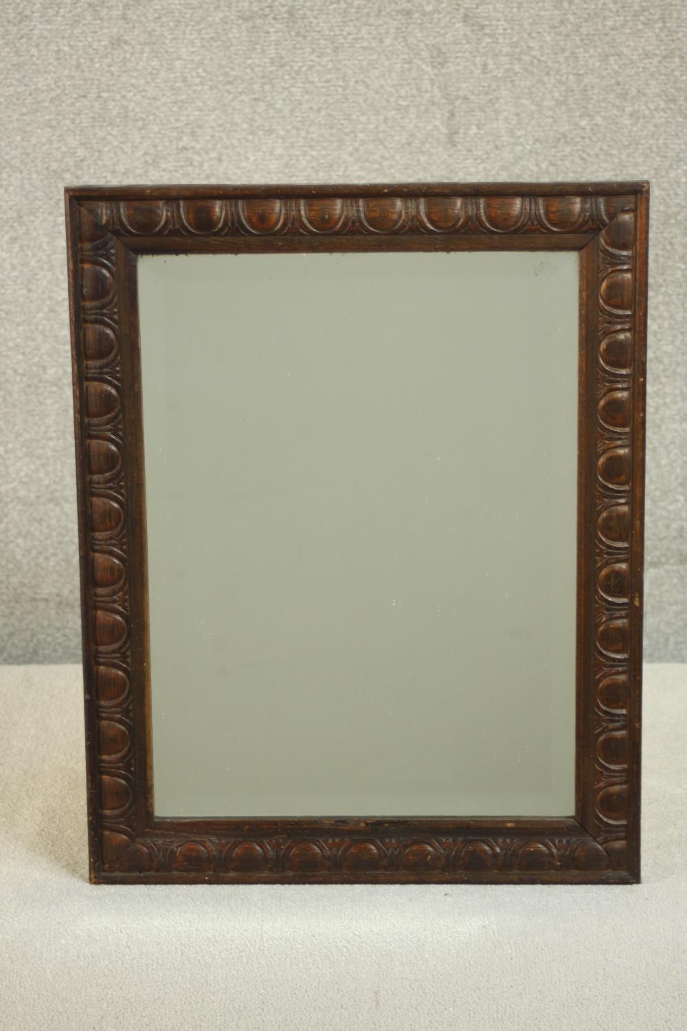 An early 20th century rectangular oak wall mirror, the frame carved with an egg and dart type
