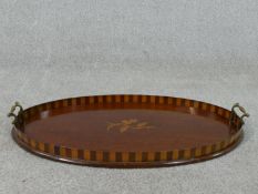 An Edwardian walnut and marquetry inlaid oval tray, with two brass handles, the centre inlaid with a