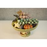 A carved alabaster pedestal fruit bowl filled with various marble and gemstone fruit and vegetables,