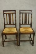 A pair of early 20th century oak dining chairs, with carved and barley twist backs over rush