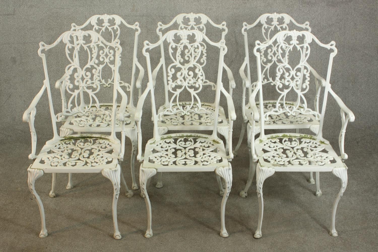 A set of six white painted cast iron carver garden chairs, with pierced splat back and open arms