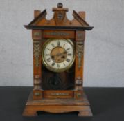 A late 19th century American stained pine mantel clock, with Roman numerals to the enamelled chapter