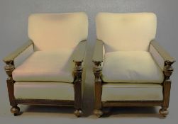 A pair of early 20th century oak armchairs, upholstered in cream fabric, with carved cup and cover