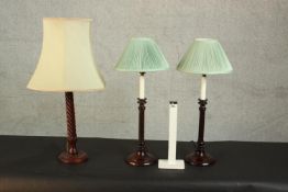 A pair of mahogany candlestick design table lamps with green silk shades along with another