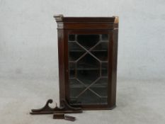 A George III mahogany corner cabinet, with a swan neck pediment over an astragal glazed door