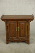 A late 20th century Chinese elm two door altar style cabinet with brass swing handles, the doors