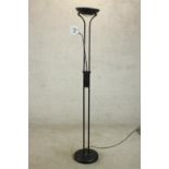 A contemporary black floor standing uplighter lamp, with a reading lamp on an adjustable arm, on a