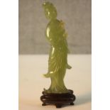 A carved Chinese jade figure of Guanyin on a carved hardwood base. (Some damage as seen). H.20 W.7
