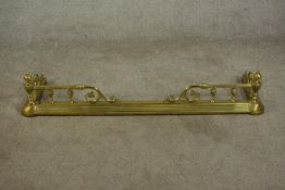 A late 19th/early 20th century brass fender, with wrythen urn supports, the rails terminating in