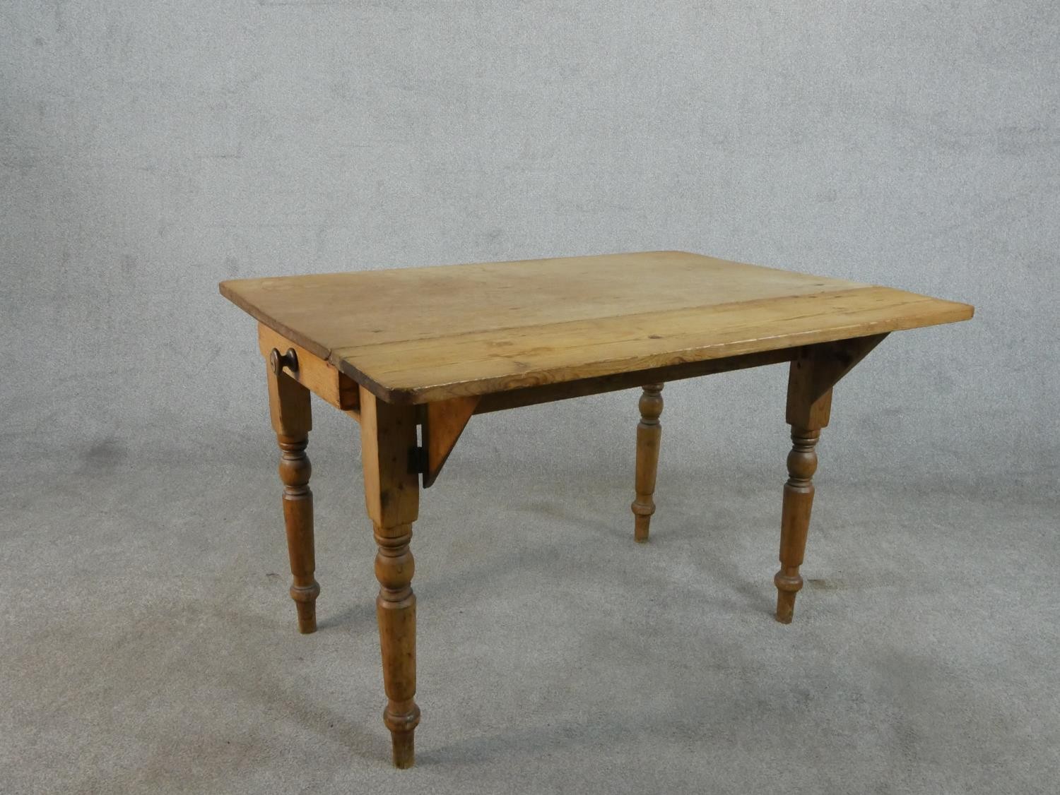 A Victorian pine kitchen table, with one drop leaf over end drawers, on turned legs. H.71 W.109 - Image 7 of 7