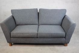 A contemporary two seater sofa upholstered in grey fabric, with loose back and seat cushions, on