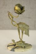 An Oriental brass candlestick in the form of a figure of a stork holding a flower, standing on a