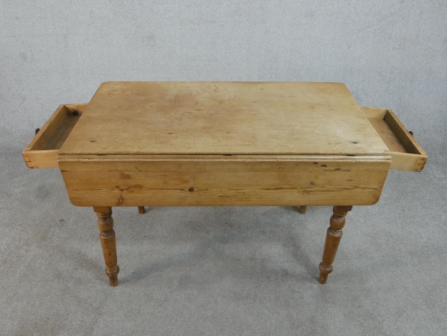 A Victorian pine kitchen table, with one drop leaf over end drawers, on turned legs. H.71 W.109 - Image 4 of 7