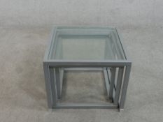 A contemporary nest of three occasional tables, of square form with plate glass tops and square