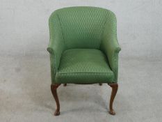 An early 20th century walnut tub chair, upholstered in green fabric, on carved cabriole legs.