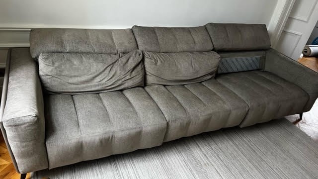A very large contemporary Roche Bobois fully reclining sofa upholstered in grey fabric, on splayed