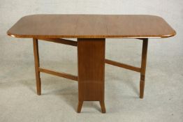 A mid 20th century walnut drop leaf dining table, the two leaves with rounded corners on a base with