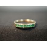 A yellow metal (tests as 18ct) emerald half eternity style ring, set with seven rectangular