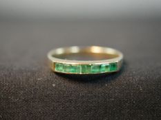 A yellow metal (tests as 18ct) emerald half eternity style ring, set with seven rectangular