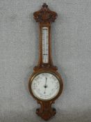 A late Victorian carved walnut aneroid banjo barometer, with an enamelled circular barometer dial,