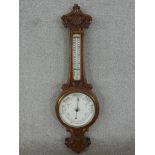 A late Victorian carved walnut aneroid banjo barometer, with an enamelled circular barometer dial,