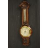 A circa 1900's Negretti & Zamba carved oak barometer and thermometer with shell and flower motifs.