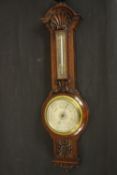 A circa 1900's Negretti & Zamba carved oak barometer and thermometer with shell and flower motifs.