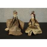 Two early 20th century Japanese dolls on hardwood stands. The heads painted ceramic with silk