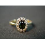 An early 20th century 18 carat closed back green stone oval cluster ring, set to centre with an oval