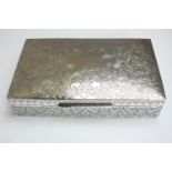 A large cedar lined white metal (tests as silver) cigarette box with an all over engraved flora