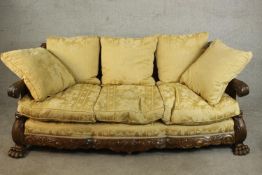 An early 20th century Continental carved walnut three seater bergere sofa, upholstered in gold