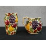 A Siltone pottery hand painted relief fruit design jug and matching flower vase, stamped to base.